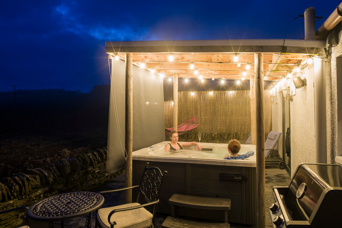 The Romantics hot tub at night with privacy screen